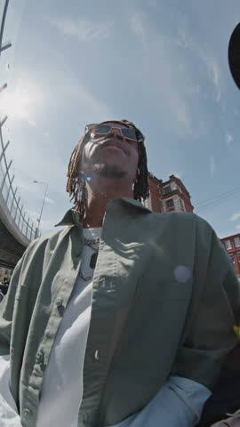 Vertical low angle shot of two African American hipsters having gang thing outdoors, having heated conversation with someone in street