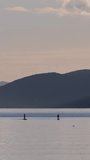 Silhouette of couple standing on a SUP board and exercising at sunset. Active people stand up paddling and enjoy tropical evening sunshine in Mediterranean Sea. Sporty vacation or holiday concept.
