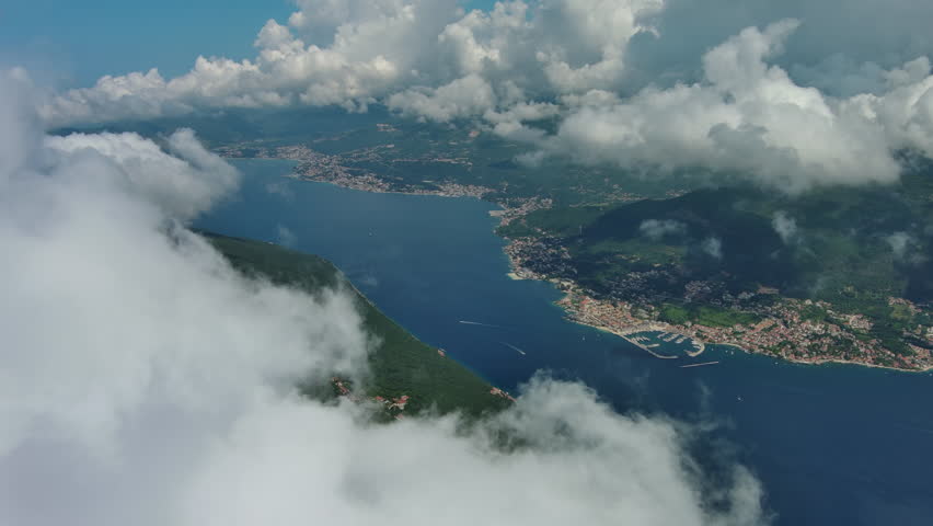 Aerial view on clouds over Kotor Bay, Montenegro. Flying in clouds over sea bay, 4k