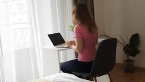 woman working at home on a computer, talking on the phone, businesswoman or student looking at laptop learning, serious girl working or studying computer doing research or preparing for exam online.