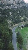 Drone video captures car journey on mountain road through forest, showcasing road trip, driving. Emphasizes adventure of road trip, driving. Tailored for fans of road trip driving in natural settings
