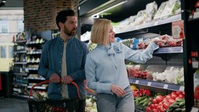 Front view of friendly caucasian family couple engaging in shopping process together in supermaket setting. Lovely husband putting tomatoes in cart while adorable wife consulting with him indoors. - Powered by Shutterstock - Get 15% off with code: PIKWIZARD15