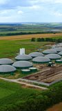 Biogas plant. Contemporary farm for biomass production surrounded by green environment. Modern agriculture for organic gas on field. Vertical video