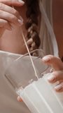 A young woman with braided hair, dipping strawberries on a skewer into white chocolate. Slow motion. Vertical video.