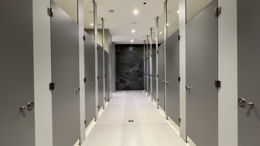 Contemporary Public Restroom with Rows of Closed Stall Cubicles and Partitions Lining Both Sides Royalty-Free Stock Footage #3467894685