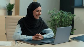 Happy Arabian business woman muslim islamic businesswoman in hijab female employer manager consultant teacher tutor talk video call laptop online conference computer internet communication in office