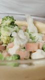 Vertical video. The woman slowly spreads the filling made of colorful cabbage, leeks, and pieces of salmon onto the dough for the vegetable pie.