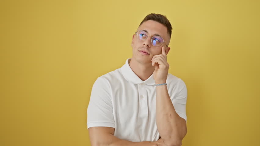 Exciting moment when happy young hispanic man in glasses, gesturing the number one, has a brilliant idea, standing isolated on yellow background, his face beaming with clever success