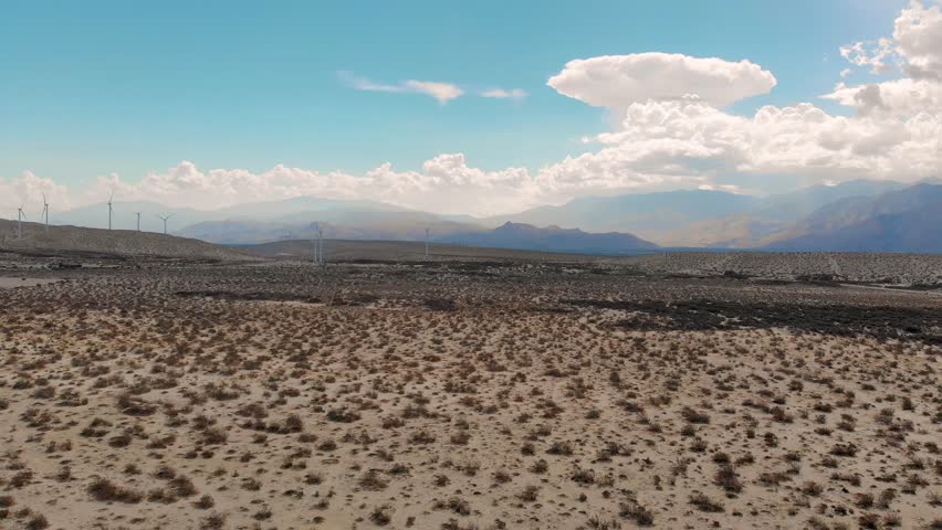 Pan down over desert brush and wind mills near small town
