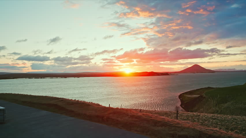 Panoramic view of beautiful sunset in Iceland. Picturesque Icelandic landscape at dusk. Colorful cloudscape. View of wide river streaming along the landmark.