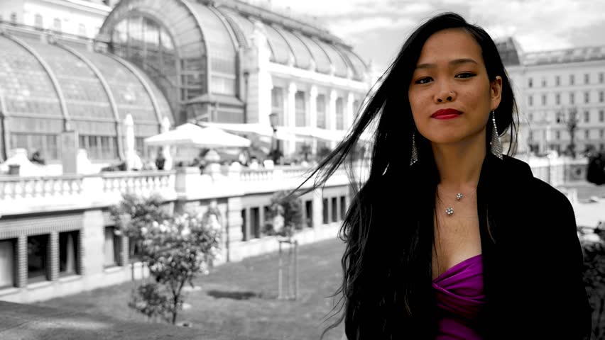 Young dark haired girl smiling and posing in front of the Palmenhaus in Vienna, medium close up, slowmotion.