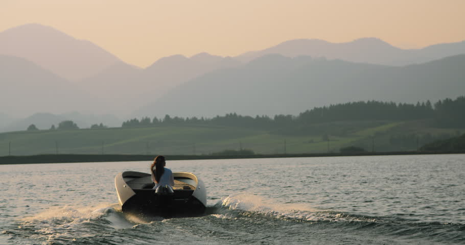 Three birds cross the path of the boat as it glides over the lake in slow motion during the evening.