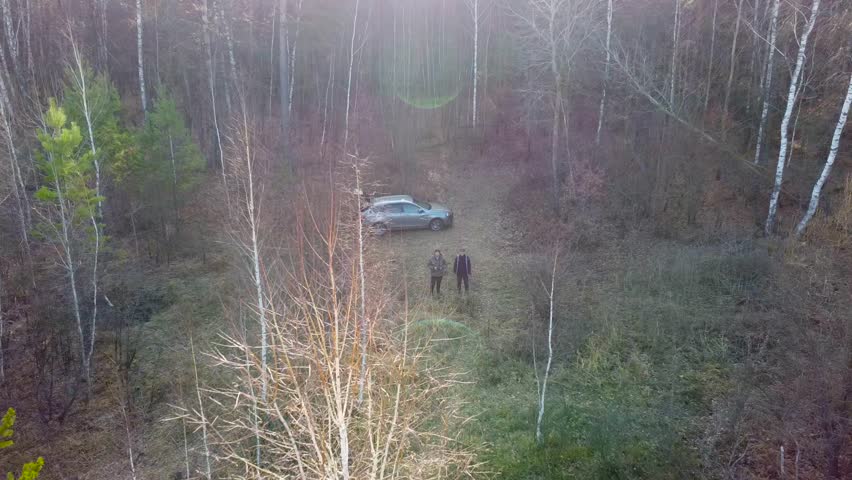 Two men, father and son, stand in the autumn forest. Traveling family in nature. Two tourists look into the drone camera as they take off against the backdrop of an autumn landscape. Tourist trip