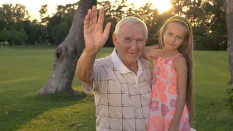 Grandfather and girl waving with hands. People showing greeting gesture. Happy family relationship.