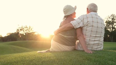 Senior woman kissing her man outdoors. Romance between elderly couple, back view. Man and woman outdoor. Give me a kiss.
