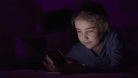 Child Using Mobile Phone Evening at Home. Teen Girl Watching Online Video Social Media on Smartphone in Bed in Bedroom at Night. Dependence on Social Networks in Children. Not Healthy Sleep.