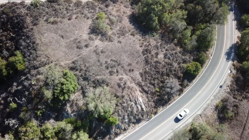 Aerial footage of the dry Southern California vegetation with cars driving on a curvy canyon road. Trabuco Canyon, Orange County, California USA Royalty-Free Stock Footage #3468391553