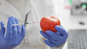 A scientist injects a tomato with a syringe in a laboratory setting, portraying biotechnology research. - Powered by Shutterstock - Get 15% off with code: PIKWIZARD15