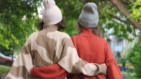 Two girlfriends are walking and hugging outside in an autumn park. Rear view of two girls walking among autumn trees in a city park. - Powered by Shutterstock - Get 15% off with code: PIKWIZARD15