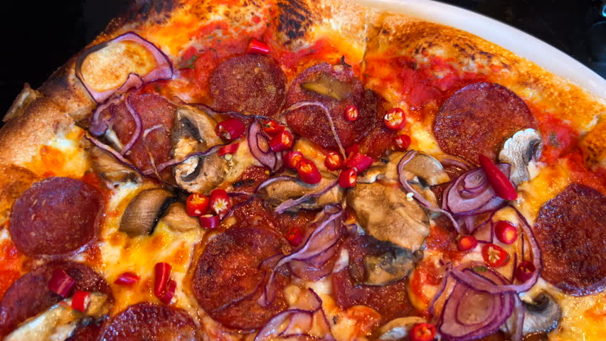 Traditional Italian spicy pepperoni pizza with fresh chili peppers, red onions and mushrooms, real authentic Neapolitan pizza, delicious food, 4K shot
