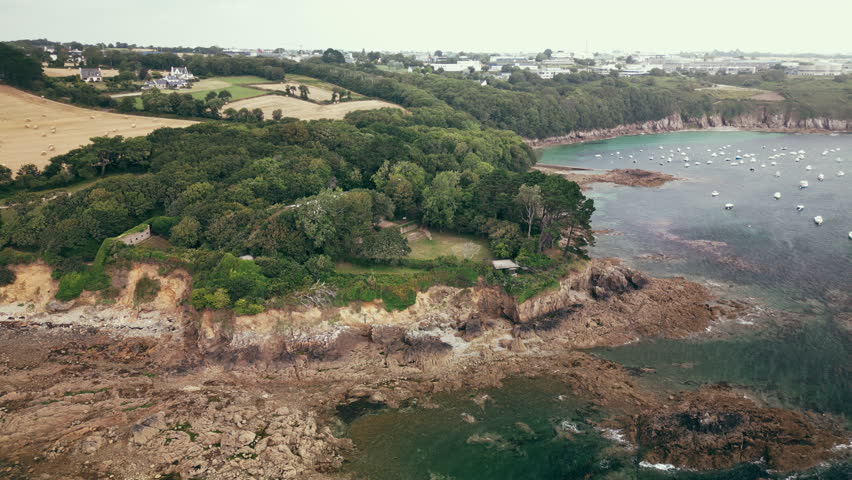 Downward Arc Aerial of a Ruined Castle with Large White Marquee on Ocean Coastline