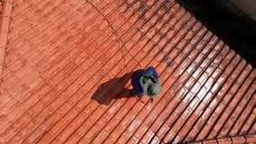 A person outdoors cleaning the red clay roof using a high pressure washer. Professional washing house tiles with water hose. - Powered by Shutterstock - Get 15% off with code: PIKWIZARD15