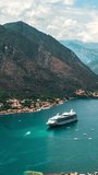Amazing panoramic vertical hyperlapse video of the picturesque bay of Kotor bay with old town, with beautiful coastline, and cruise ship entering the port, yachts and boats ply the bay.