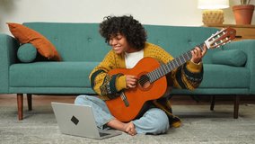 Blogger guitarist. Happy African American girl blogger playing guitar singing song recording vlog. Social media influencer woman streaming recording at home studio. Music content creator broadcast