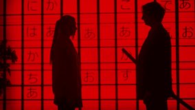 People against big digital wall in studio. Silhouettes of man giving woman japanese sword katana in front of digital screen red asian graphic background.