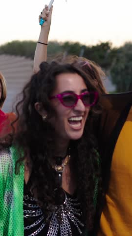 Vertical of a group of LGBT people is leisurely walking down the street in the gay pride day parade holding colorful rainbow flags, enjoying a fun and happy event. Diverse men and women run together