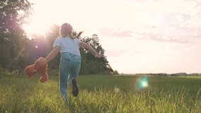 Little girl with a toy teddy bear in park. Cute girl with a teddy bear in a green field. Lonely girl with a toy teddy bear in park in green field.Teddy bear in the hands of a girl in the park - Powered by Shutterstock - Get 15% off with code: PIKWIZARD15