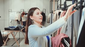 Young woman in chic blazer enthusiastically browses through variety of clothes in fashion store. Spirit of shopaholic - Powered by Shutterstock - Get 15% off with code: PIKWIZARD15