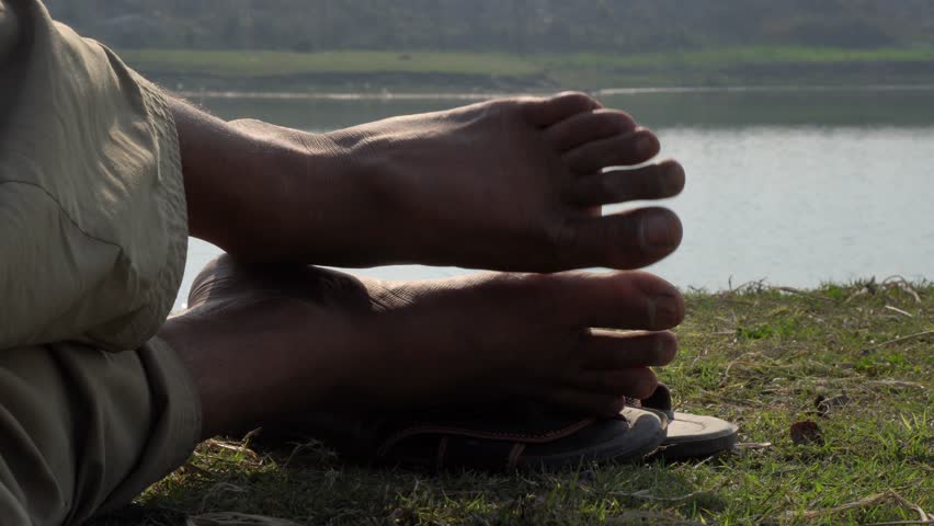 Feet of a man lying on the beach in 4k resolution. Young man lying in a camp tent closed up point of view on male legs with sea view on stunning beach at sunset.
