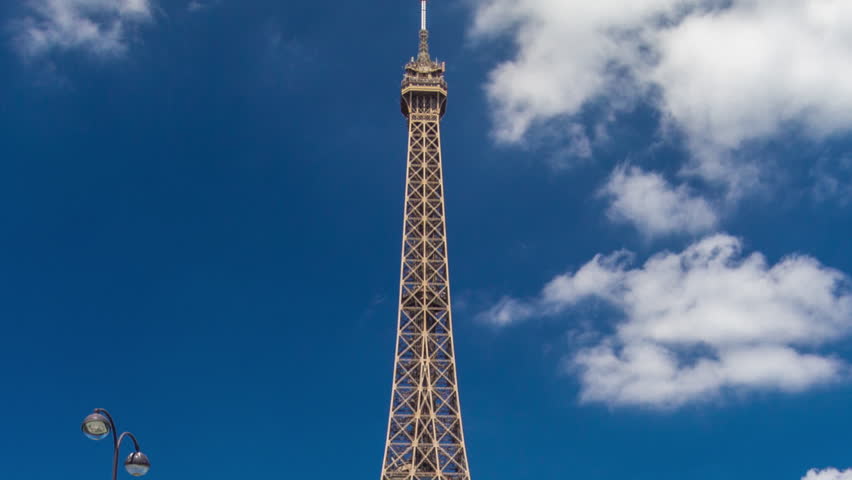 Eiffel Tower on Champs de Mars in Paris timelapse hyperlapse, France. Blue cloudy sky at summer day with green lawn and fountain with traffic around Royalty-Free Stock Footage #3468989271