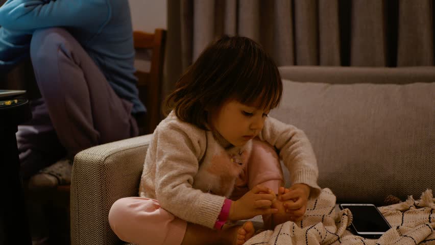 The baby is picking at his toes. cleans fingers. Evening at home.