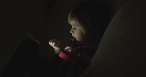Boy enjoy digital tablet at night, sitting on sofa, in the living room