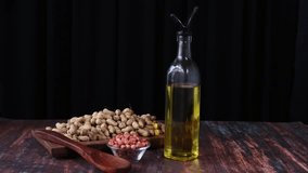 Super slow motion macro of fresh bio organic dried cleaned peanuts are falling on wooden rustic table in kitchen of restaurant with oils in a container