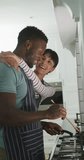 Vertical video of happy diverse couple cooking at home. family spending time together at home and body inclusivity.