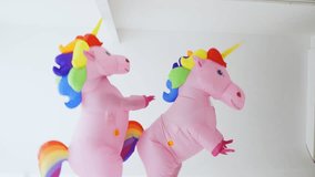 A joyful moment as two people dance in pink unicorn costumes adorned with vibrant rainbow-colored manes. - Powered by Shutterstock - Get 15% off with code: PIKWIZARD15