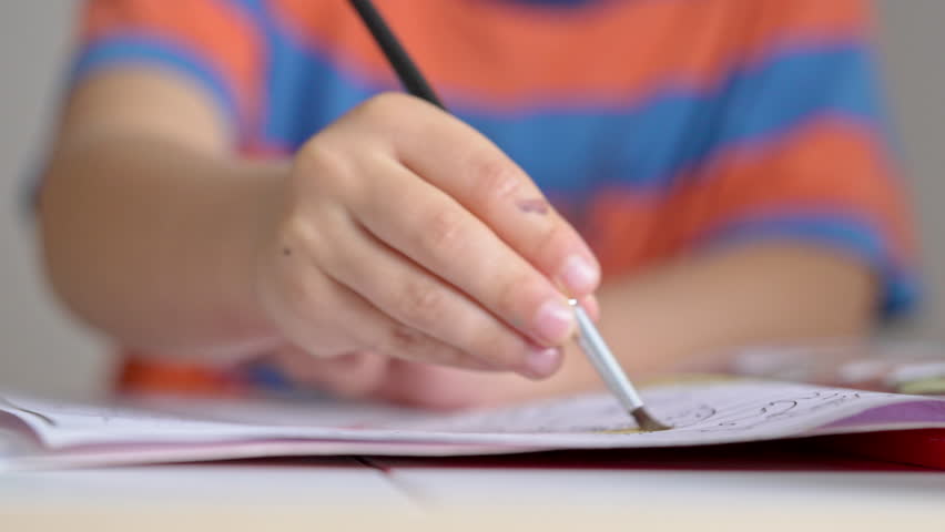 Little Boy Vigorously Paints Sketchbook Using Brush And Watercolor