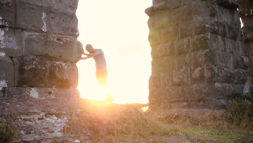 Young man in sportswear working out under ancient roman aqueduct Appio Claudio arch. Training outdoor in the park at sunset slow motion.