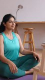 Young native ethnic indian female yoga instructor teaching breathing and meditation online exercise through video call using laptop from home studio. Vertical aspect video 9:16