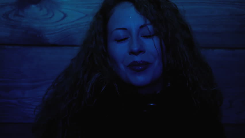 Pretty young woman with close eyes at dark room and color blue red light close-up