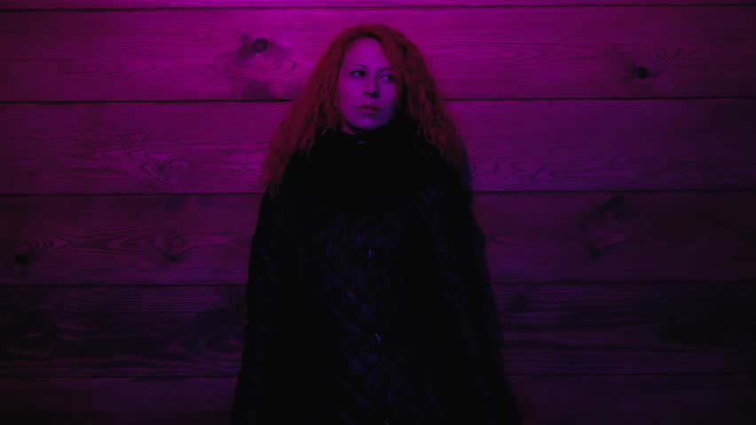 Beautiful woman stands alone at the dark room with color red blue light