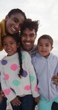 Vertical video of portrait of happy biracial family on sunny beach. healthy, active time beach holiday.