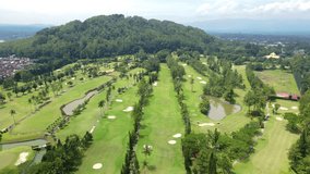 Aerial view of beautiful golf course with hill on the background. Borobudur International Golf Course with view of Tidar Mountain, Indonesia.