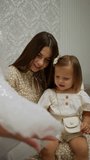 Joyful Anticipation of Littlest Bridesmaid. Smiling young girl and enthralled toddler admire sparkling details of flower girl dress in bridal store.