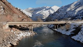 A spectacular 4K drone shot of the Colorado River and a bridge crossing, running adjacent to I-70 and an old railroad, through the Rocky Mountains of Colorado, during the winter season. - Powered by Shutterstock - Get 15% off with code: PIKWIZARD15