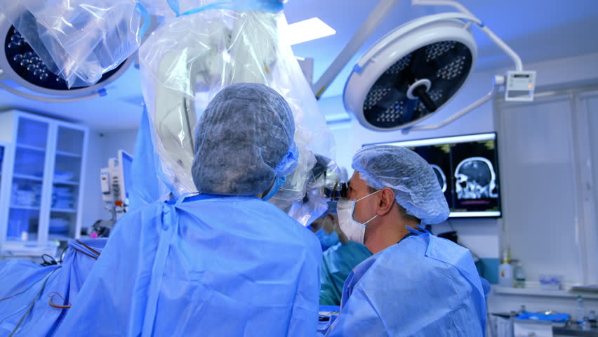 Two surgeons looking attentively at microscope during the operation. Modern neurosurgery on brain in contemporary hospital. - Powered by Shutterstock - Get 15% off with code: PIKWIZARD15