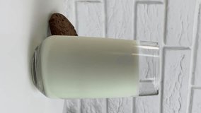 Vertical video: Milk in glass cup close-up. Glass with yogurt, dairy products concept. Drinking fresh lactose-free milk in morning.